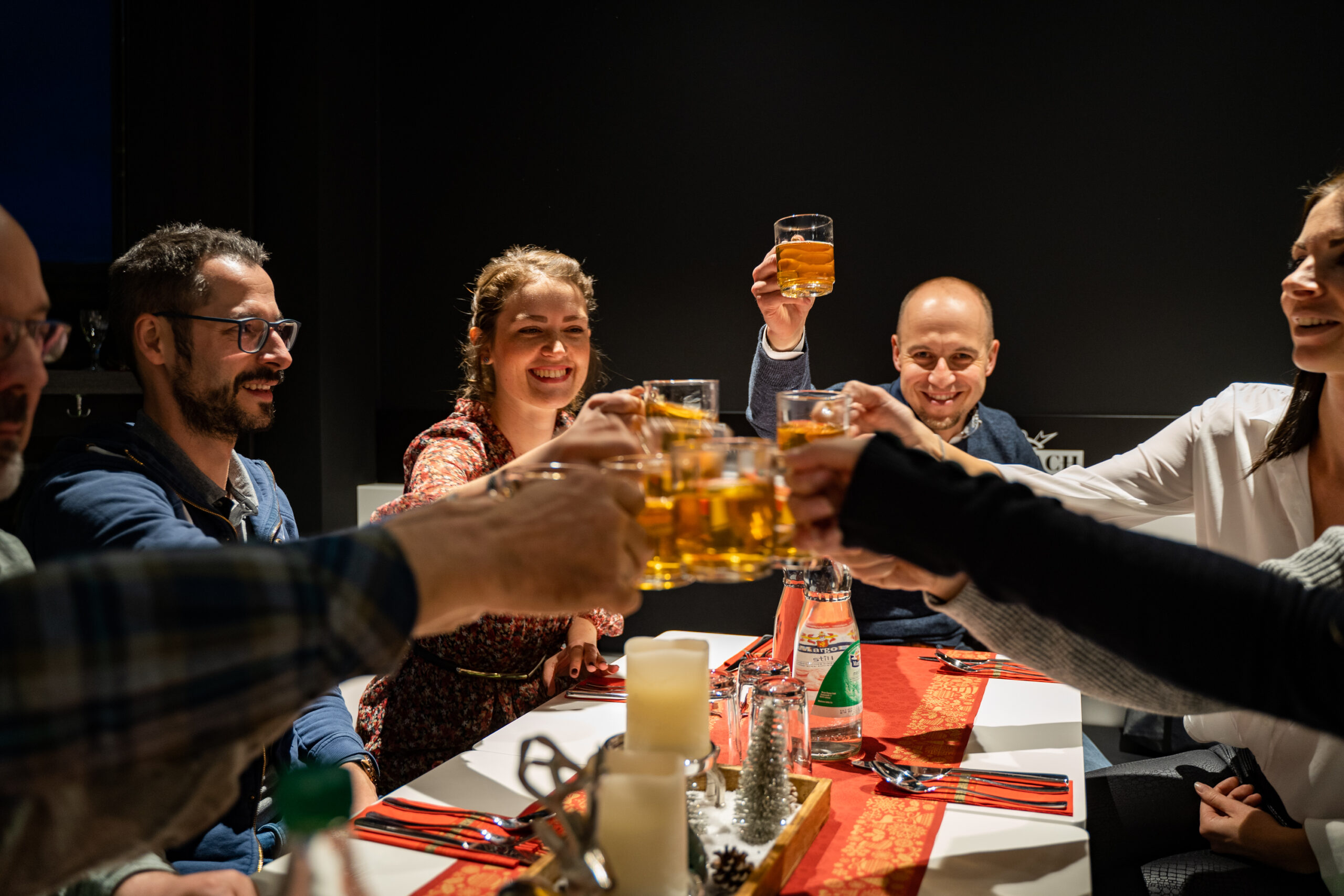 DIEP Mitarbeiter/innen sitzen am Tisch stoßen mit Glühwein an